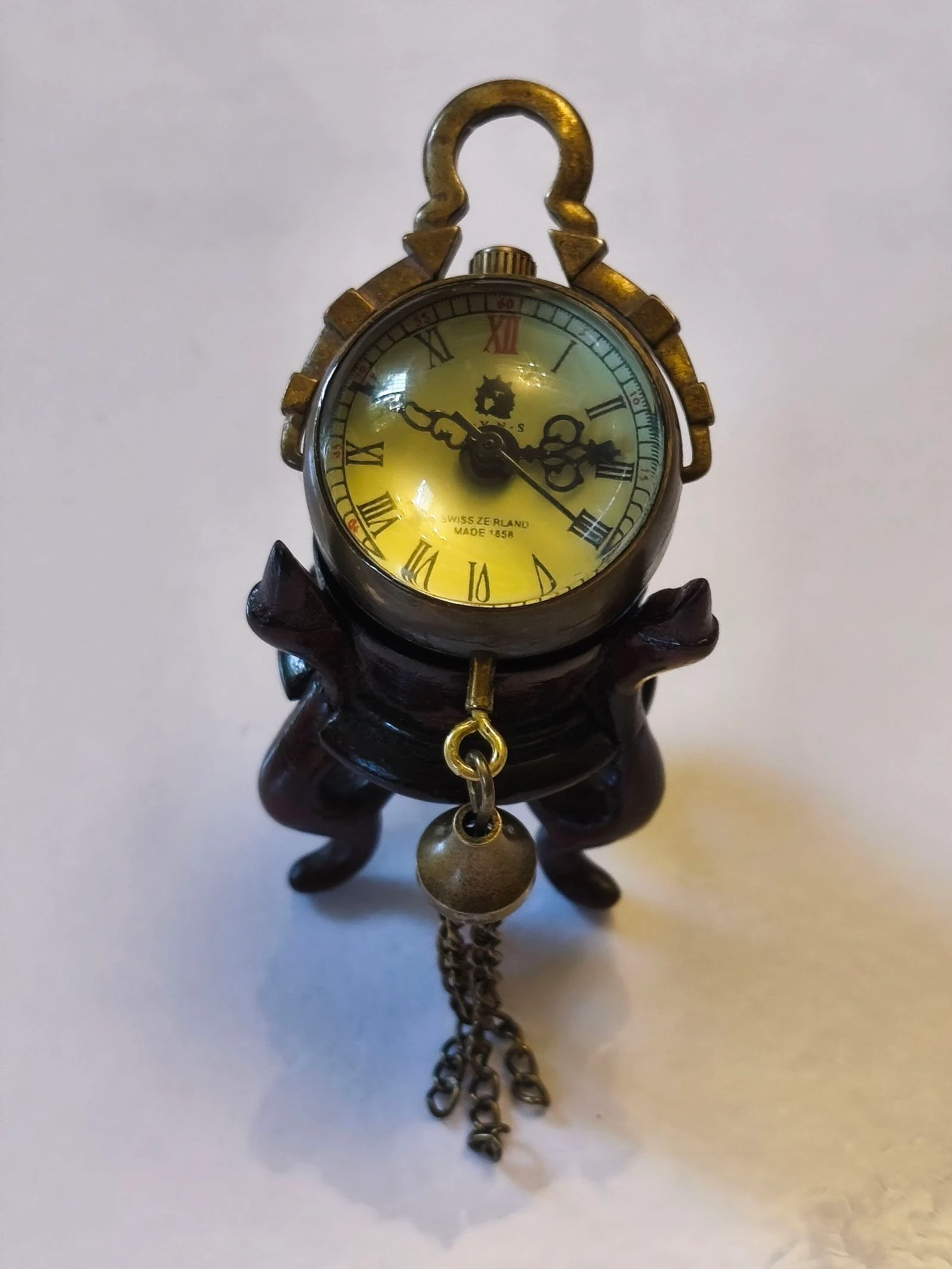 Reloj miniatura de cuerda antiguo sobre peana de madera